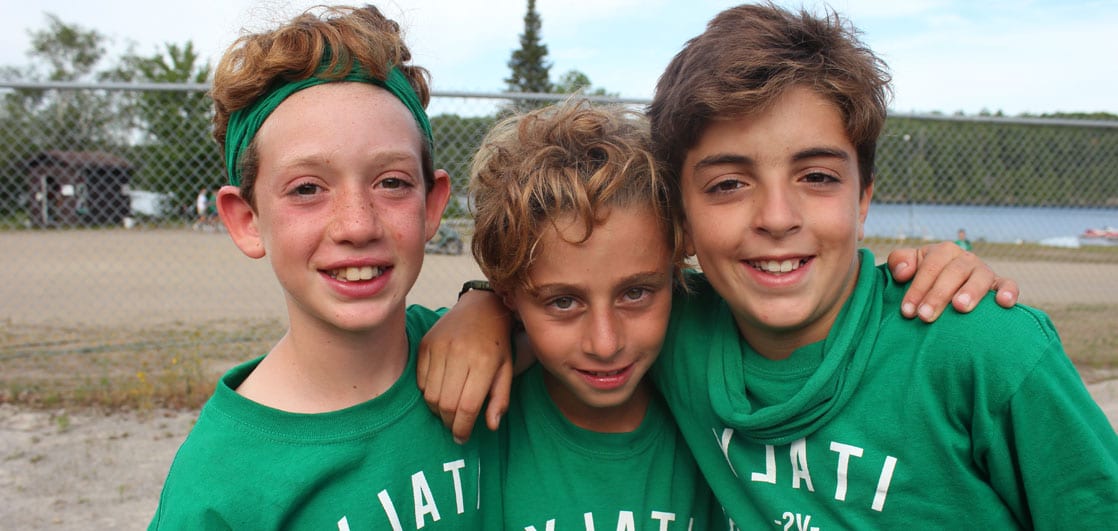 Three boys wrapping arms around each other and posing for a photo