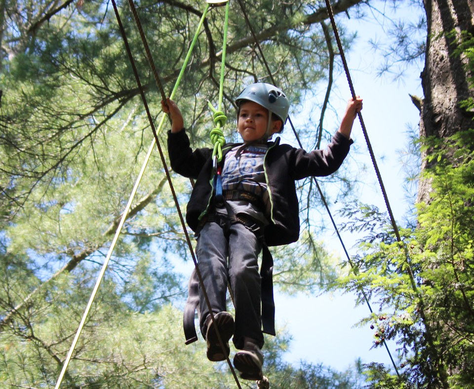 Boy walking on a rope tied to trees