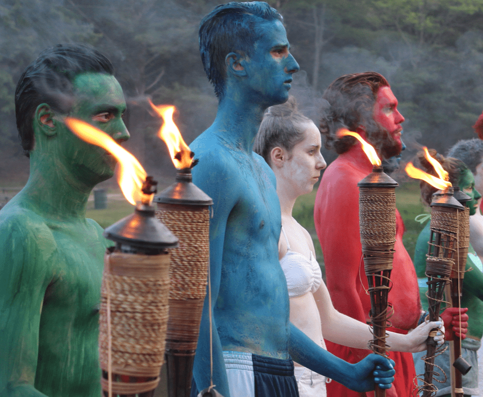 Group of people colored with body paint holding torches
