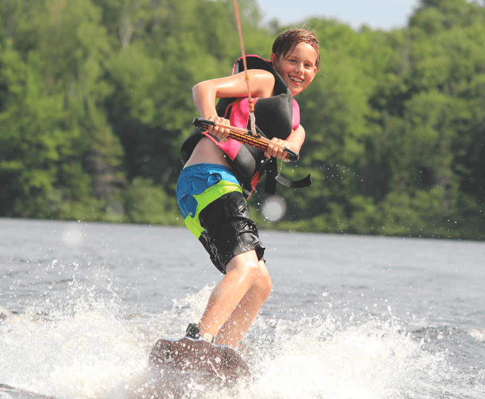 Camper wakeboarding on lake at Camp Tamarack